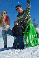 familia divirtiéndose en la nieve fresca en invierno foto