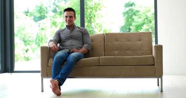 Man is Laying on Couch at Home and Using Tablet photo