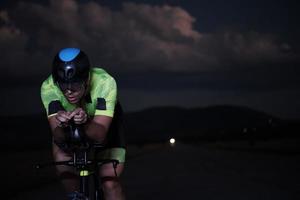 triathlon athlete riding bike fast  at night photo