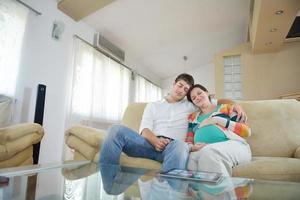 pregnant couple at home using tablet computer photo