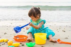 Little girl playing with beach toys during tropical vacation photo