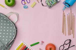 Creative flatlay of education pink table with backpack, student books, shoes, colorful crayon, eye glasses, empty space isolated on pink background, Concept of education and back to school photo