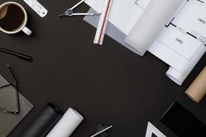 Creative flat lay of architects black table with roll blueprints, architectural project plan, engineering tools, office supplies and a cup of hot coffee, Workspace for new designer concept photo