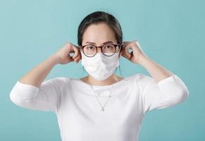 Asian young woman wearing respirator mask to protect coronavirus outbreak and washing hands with alcohol gel, New virus Covid-19 from Wuhan China concept, isolated on blue background photo