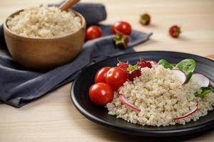 Quinoa salad with vegetables, raspberry and tomatoes on the wooden table. Super food for healthy and concept of balanced diet photo