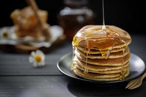 Honey dripping on the stack of pancakes for breakfast on the wooden table, healthy products by organic natural ingredients concept photo