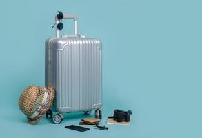 Travel Baggage with passport, camera, hat, wallet, airplane toy and smartphone isolated on blue background with copy space, Travel concept background photo