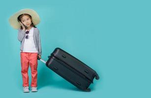 una niña asiática está usando un teléfono inteligente para verificar el vuelo para viajar los fines de semana, espacio vacío en una foto de estudio aislada en un fondo azul colorido