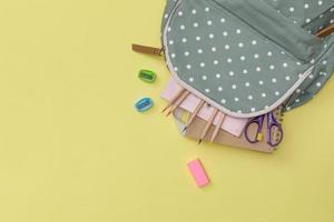 Creative flatlay of education yellow table with backpack, student books, colorful pencil, empty space isolated on blue background, Concept of education and back to school photo