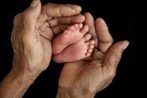 Close-up of baby's hand holding mother's finger photo