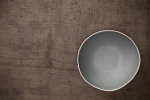 Cuenco redondo de cerámica gris en blanco vacío sobre fondo negro de mesa de madera con espacio para copiar, vista superior del concepto tradicional de utensilios de cocina hechos a mano foto