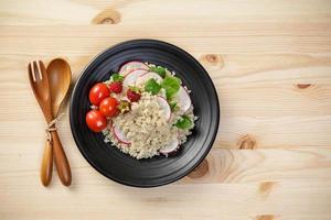 Quinoa salad with vegetables, raspberry and tomatoes on the wooden table. Super food for healthy and concept of balanced diet photo