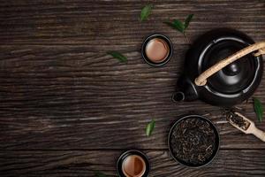 Tea cup with teapot, organic green tea leaves and dried herbs on the wooden desk empty space creative flat lay, Organic product from the nature for healthy with traditional style photo