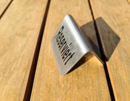 Metallic sign on a wooden table with the german word for reserved on it. photo