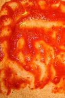 Homemage pizza dough with tomatoe sauce and no topping. photo