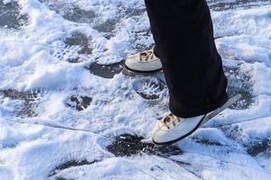 Ciérrese para arriba en los pies de las mujeres que llevan botas de patinaje sobre hielo y que se colocan en el hielo. foto