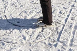 Ciérrese para arriba en los pies de las mujeres que llevan botas de patinaje sobre hielo y que se colocan en el hielo. foto