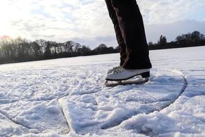 Close up on womans feet wearing ice skating boots and standing on ice. photo