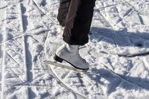 Ciérrese para arriba en los pies de las mujeres que llevan botas de patinaje sobre hielo y que se colocan en el hielo. foto