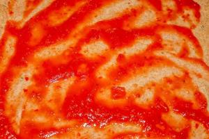 Homemage pizza dough with tomatoe sauce and no topping. photo