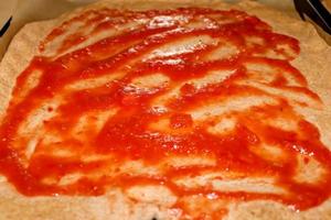 Homemage pizza dough with tomatoe sauce and no topping. photo