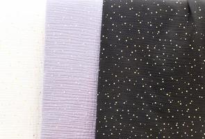 Detailed close up view on samples of cloth and fabrics in different colors found at a fabrics market photo