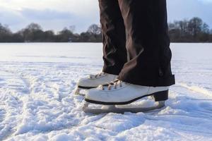 Close up on womans feet wearing ice skating boots and standing on ice. photo