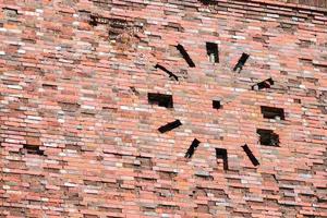Abandoned old vintage red brick wall with round clock on facade, masonry fragment photo