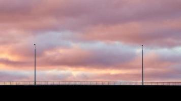 cielo rosa y violeta y siluetas de linternas en el puente foto