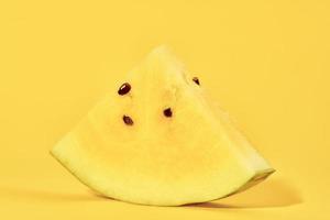 One piece of yellow watermelon with seeds on yellow background, delicious refreshing fruit photo