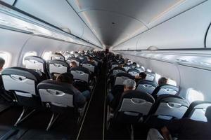 asientos de cabina de avión con pasajeros. clase económica de las nuevas aerolíneas de bajo costo más baratas. viaje viaje a otro país. turbulencia en vuelo. foto