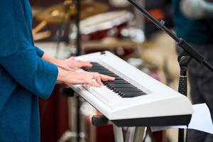 Musician woman playing on synthesizer keyboard piano, hands press synthesizer keys on concert stage photo