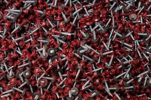 Bunch of galvanized self-drilling screws with washer and red hexagonal head, hardware background photo