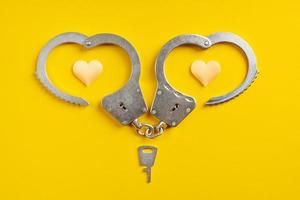 Handcuffs smile shape on yellow background. Freedom concept. photo