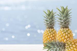 pineapple on wooden table and sea blur background photo