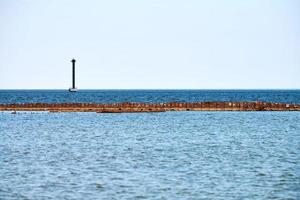 Old abandoned rusty sea pier for mooring boats and yachts on background of calm blue sea, horizon photo
