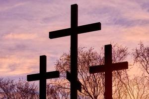 Three crosses in silhouette at sunset, dramatic sky