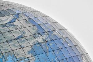 edificio moderno esférico de vidrio con reflejo de cielo azul foto