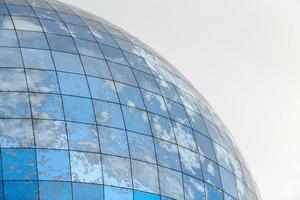 edificio moderno esférico de vidrio con reflejo de cielo azul foto
