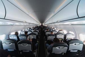 Airplane cabin seats with passengers. Economy class of new cheapest low-cost airlines without delay or cancellation of flight. Travel trip to another country. photo