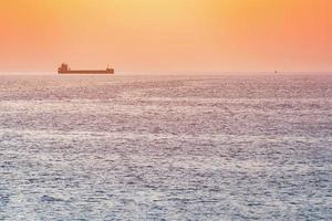 pequeño remolcador y gran carguero. hermosa puesta de sol sobre el mar. impresionante vista de viaje, espacio de copia. foto