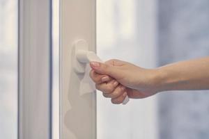 la mano femenina abre y cierra la ventana de plástico. de cerca. foto