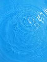 desenfoque borroso transparente color azul claro agua tranquila textura superficial con salpicaduras y burbujas. fondo de naturaleza abstracta de moda. ondas de agua a la luz del sol con espacio de copia. acuarela azul brillante foto