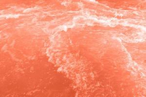 Defocus blurred transparent orange colored clear calm water surface texture with splash, bubble. Shining orange water ripple background. Surface of water in swimming pool. Orange bubble water, splash. photo