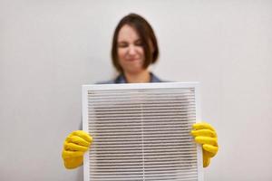 Woman holding dirty and dusty ventilation grille, disgusted photo