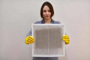mujer sosteniendo una rejilla de ventilación sucia y polvorienta, borrosa. foto