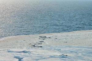 Melting sea ice seasonal natural phenomenon of coming spring, ice on water melts from burning sun photo