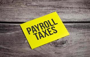Payroll Taxes written on yellow paper note photo