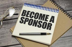 BECOME A SPONSOR text on wooden background photo