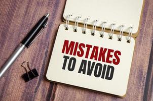 mistakes to avoid text on the paper notebook and pen on wooden background photo